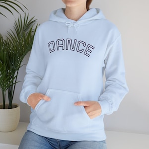 Könnte beinhalten: Ein hellblauer Kapuzenpullover mit dem Wort DANCE in dunkelblauer College-Schrift auf der Brust. Das Kleidungsstück verfügt über eine Kängurutasche auf der Vorderseite, lange Ärmel mit gerippten Bündchen und eine passende Kapuze mit Kordelzug.