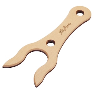 May include: A light-colored wooden tool with a Y-shaped design featuring two curved prongs, a central circular hole, and a circular hole at the handle end. The word Sujur is engraved in a cursive script on the surface of the wooden handle.