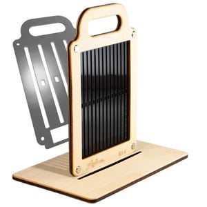 May include: A light-colored wooden vertical slicing tool with a handle and a black slotted insert, featuring the text "Fyfus" and "RH 8" engraved on the front. A separate grey metal plate with vertical slots is positioned behind the main wooden unit.