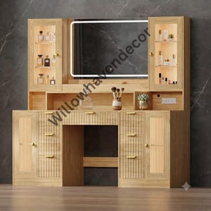 May include: A light wood vanity table featuring a large rectangular mirror with integrated LED lighting, two glass-fronted upper cabinets, and lower storage cabinets with vertical fluted detailing and gold-toned hardware handles.