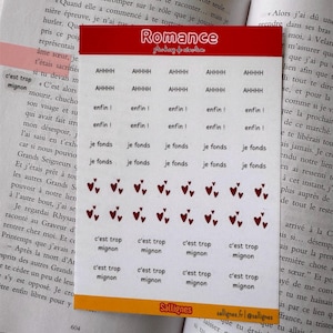 Peut inclure: Une planche d'autocollants rectangulaire avec une en-tête rouge marquée Romance et un pied de page jaune marqué Sallignes. La planche contient des rangées de petits autocollants avec le texte AHHHH, enfin, je fonds, des cœurs rouges.