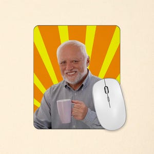 May include: A rectangular mouse pad featuring a printed image of an older person with white hair and a beard, wearing a light grey button-down shirt and holding a light purple mug, set against a background of yellow and orange sunburst rays.