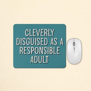 May include: A rectangular teal mouse pad featuring the white text "CLEVERLY DISGUISED AS A RESPONSIBLE ADULT" in a clean sans-serif font, positioned next to a white computer mouse with a central scroll wheel and two primary buttons.