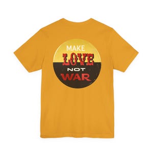 May include: A mustard yellow short-sleeve t-shirt featuring a circular graphic on the back. The circle is split horizontally with a yellow top and black bottom, displaying the white and red text MAKE LOVE NOT WAR in a stylized font.