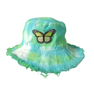 May include: A green and blue tie-dye bucket hat with a frayed edge and a green butterfly patch.