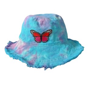 May include: A blue and purple tie-dye bucket hat with a pink and red butterfly patch.