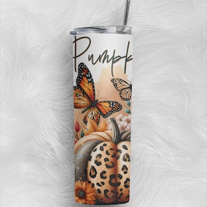 May include: A cylindrical stainless steel tumbler with a lid and metal straw. The design features a large orange monarch butterfly, a leopard print pumpkin, a sunflower, and autumn leaves. The word Pumpkin is written in black script.