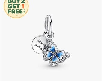 Peut inclure: Un charm en argent représentant un papillon aux ailes en émail bleu et pierres transparentes, fixé à un disque circulaire en argent gravé du texte One of a kind. Le charm comprend une bélière en argent pour l'attacher à un bracelet ou une chaîne.