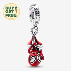 Könnte beinhalten: Ein silberner Charm-Anhänger in Form einer hängenden Spider-Man-Figur mit roter Emaille und schwarzem Spinnennetz-Muster. Die obere Öse ist mit dem Text PANDORA und SPIDER-MAN graviert. Der Anhänger hat eine polierte, metallische Oberfläche.