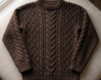 May include: A dark brown long-sleeve sweater featuring a complex cable knit pattern across the front and sleeves. The garment has a ribbed crew neckline, ribbed cuffs, and a ribbed hem, showcasing a dense, textured knit construction throughout.