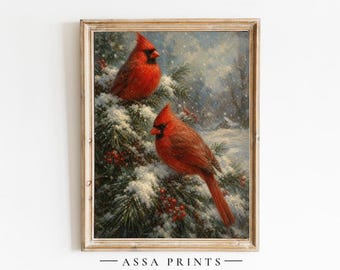 May include: A framed art print featuring two bright red northern cardinal birds perched on snow-covered pine branches with red berries. The scene depicts a winter landscape with soft falling snow. The text "ASSA PRINTS" is printed below the image.