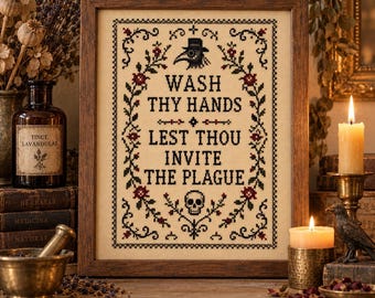 Könnte beinhalten: Ein gerahmtes Kreuzstich-Stickbild auf cremefarbenem Stoff mit einem schwarzen Pestdoktor-Maskensymbol, einem Totenkopf und dem Text "WASH THY HANDS LEST THOU INVITE THE PLAGUE" in schwarzer Schrift, umrahmt von schwarzen Ranken und roten Blüten.