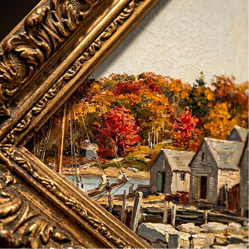 May include: An oil painting in a thick, ornate gold frame depicting a coastal scene with grey wooden sheds, a small boat at a dock, and a dense forest with vibrant autumn foliage in shades of red, orange, and yellow under a pale sky.