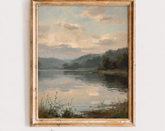 May include: A framed landscape painting depicting a calm lake at dusk with soft blue and beige clouds in the sky, dark green trees along the shoreline, and tall grasses in the foreground. The text ASSA PRINTS is visible below the frame.