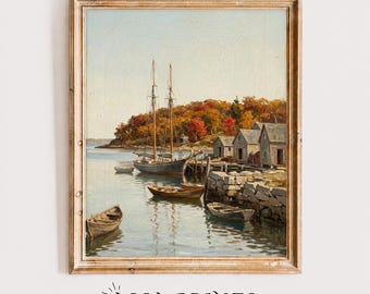 May include: A framed oil painting print depicting a coastal harbor scene with a sailboat, several small rowboats, and wooden buildings along a rocky shoreline. The landscape features trees with autumn foliage in shades of orange, red, and yellow.