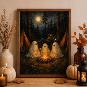 May include: A framed wall art print depicting three white ghosts sitting around a campfire in a forest at night. A skeleton rests in a hammock between two tents under a full moon. The scene features dark trees, orange tent fabric, and glowing embers.
