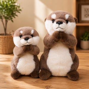 Peut inclure: Deux peluches loutres en fourrure douce marron et crème. Les deux animaux en peluche sont debout, les pattes avant jointes près de la poitrine. Ils ont des yeux sombres, de petits nez noirs et des taches blanches au-dessus des yeux.