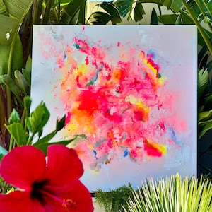 May include: A square canvas painting featuring an abstract composition of vibrant neon pink, bright orange, and yellow paint splatters against a pale white background, with subtle accents of blue and grey integrated into the textured paint layers.