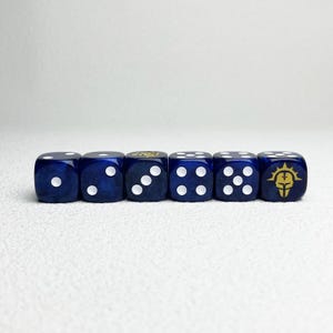Puede incluir: Un conjunto de seis dados azules translúcidos dispuestos en una fila horizontal. Cada dado presenta puntos blancos que representan los números del uno al cinco, mientras que el sexto dado muestra un emblema de casco dorado con un diseño de sol.