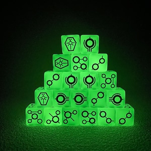Könnte beinhalten: Ein pyramidenförmiger Stapel aus zwanzig durchscheinenden, im Dunkeln leuchtenden grünen Würfeln. Jeder Würfel zeigt schwarze, eingravierte Symbole, darunter geometrische Formen, kreisförmige Muster und stilisierte sargartige Symbole mit strahlenden Linien.