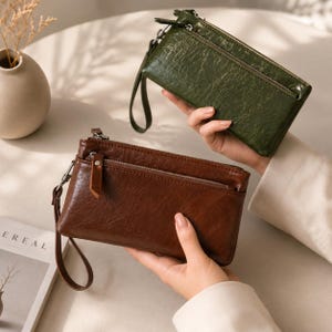 Peut inclure: Deux pochettes rectangulaires avec une texture brillante et froissée. L'une est vert olive foncé et l'autre est marron chocolat. Chaque pochette dispose d'une fermeture éclair supérieure, d'une poche frontale zippée et d'une dragonne assortie.