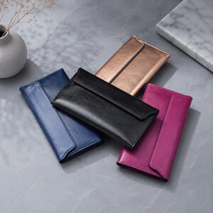May include: A collection of four rectangular wallets in blue, black, metallic bronze, and magenta. Each wallet features a smooth, solid-coloured exterior with a flap closure that extends across the front, showcasing a clean and structured design.