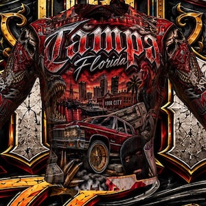 May include: A long-sleeved shirt featuring a vibrant red and black graphic print. The design includes the text "Tampa Florida" above a cityscape, a classic red car, and skull motifs. The intricate artwork covers the entire front and sleeves.