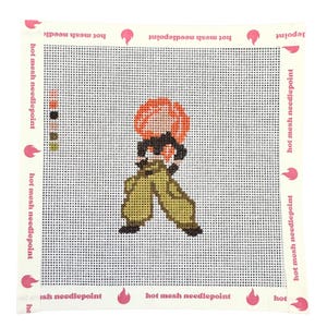 Op de afbeelding: Een vierkant naaldpunt canvas met een centrale afbeelding van een figuur met oranje haar, een zwart bovenstuk en een olijfgroene broek. De witte rand toont de herhalende tekst hot mesh needlepoint en roze vlamiconen, met een kleurlegenda links.