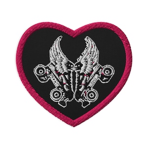 May include: A heart-shaped embroidered patch with a black background and a bright pink stitched border. The design features two white roller skates with detailed wings, positioned symmetrically to face each other in the center of the heart.