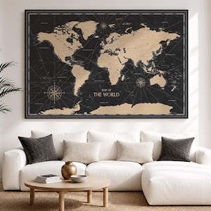 May include: A rectangular wall art print featuring a world map with tan-colored continents set against a dark black background. The map includes thin white navigational lines, compass roses, and the text MAP OF THE WORLD in white lettering.