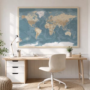 Puede incluir: Un gran mapa del mundo rectangular como arte de pared con un fondo de océano azul apagado y masas terrestres de color tostado, enmarcado en madera clara. El mapa muestra etiquetas geográficas detalladas y una rosa de los vientos.