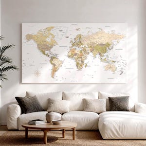 Peut inclure: Une grande impression murale rectangulaire représentant une carte du monde détaillée dans des tons sourds de beige, de brun clair et de vert tendre. La carte affiche les continents, les pays et les océans avec des étiquettes en noir.