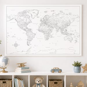 Può includere: Una grande mappa murale rettangolare del mondo con linee nere su sfondo bianco. La mappa mostra continenti, paesi e oceani con etichette chiare. Una rosa dei venti è posizionata nell'angolo in basso a sinistra della mappa.