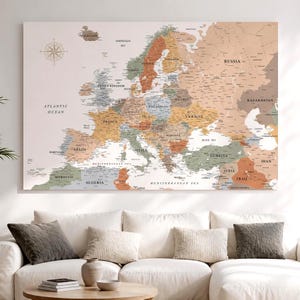 Peut inclure: Une carte murale rectangulaire de l'Europe et des régions environnantes présentant une palette de couleurs douces composée de beige, de vert sauge et de terre cuite. La carte inclut une rose des vents et des noms de pays clairement indiqués.
