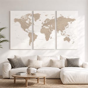 Peut inclure: Un ensemble de trois panneaux muraux représentant une carte du monde avec des continents beiges sur fond blanc. La carte affiche les continents et les noms géographiques dans une palette de couleurs neutres, sous forme de triptyque vertical.