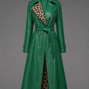 Puede incluir: Una gabardina larga de color verde esmeralda con cierre de doble botonadura, botones metálicos, un cinturón a juego en la cintura y un forro con estampado de leopardo visible en las solapas y en el interior de la prenda.