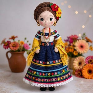 May include: A handcrafted crochet doll featuring brown braided hair adorned with red and yellow flowers. The doll wears a white off-the-shoulder top, a navy blue skirt with colorful floral embroidery, a yellow shawl, and gold hoop earrings.