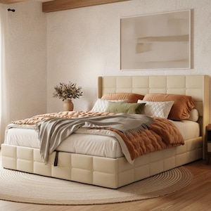May include: A cream-colored upholstered bed frame with a tufted headboard and base. The bed is dressed with white sheets, a textured rust-colored quilt, a gray throw blanket, and several pillows in white, rust, and olive green tones.