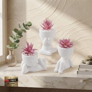 May include: Three white ceramic planters shaped like human figures in different poses, each containing a small pink succulent plant. The planters are arranged on a surface alongside a clear glass vase holding green eucalyptus stems.