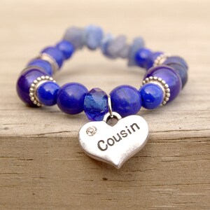 May include: A blue and silver beaded bracelet with a heart-shaped charm that says "Cousin".