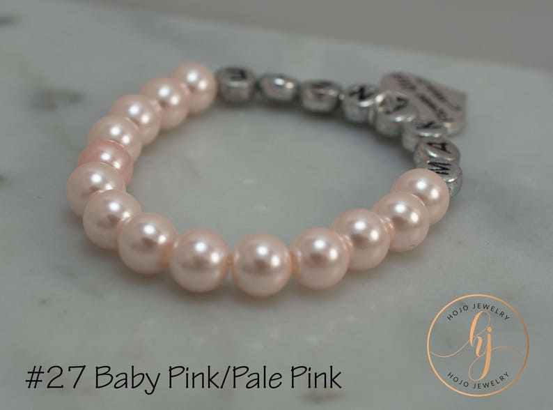 May include: A pale pink pearl bracelet with a silver charm that says "Mommy's Little Girl".