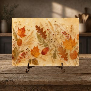 May include: A rectangular resin plaque featuring embedded pressed autumn leaves, ferns, and red berries in shades of orange, yellow, and brown. The piece is displayed on a dark metal stand, showcasing a botanical arrangement with gold flecks.