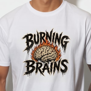 May include: A white short-sleeved t-shirt featuring a graphic print of a human brain surrounded by orange and yellow flames. The text BURNING BRAINS is printed in a jagged, black, distressed font above and below the brain illustration.