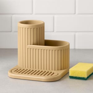 Peut inclure: Un organisateur d'évier beige doté d'un compartiment cylindrique haut et d'une section rectangulaire plus basse avec des détails nervurés verticaux. La base comprend un plateau de drainage rainuré et une éponge jaune rectangulaire avec une couche abrasive verte.