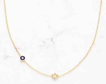 May include: A gold chain necklace with a blue evil eye charm and a gold star charm.