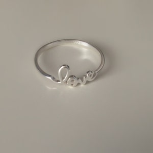 May include: A silver ring with the word "love" written in cursive.
