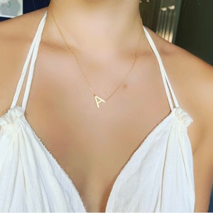 May include: A gold necklace with a simple, flat, capital letter 'A' pendant.