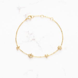 May include: Gold chain bracelet with a star and the letters 'L', 'O', and 'V' set with small clear stones.