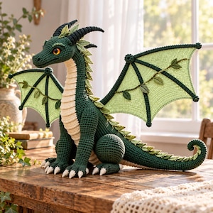 May include: A crocheted dragon plush toy featuring a dark green body, a cream-colored underbelly, and light green wings adorned with small leaf-like accents. The creature has black horns, orange eyes, and white claws, with a long tail and a row of small green leaves running down its back.