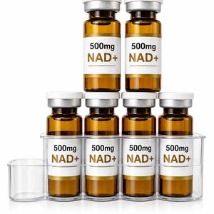 Op de afbeelding: Zes amberkleurige glazen flesjes met witte doppen en etiketten met de tekst 500mg NAD+, geplaatst in een doorzichtige kunststof houder. Twee flesjes staan bovenop vier flesjes op een rij. De etiketten bevatten zwarte tekst voor de dosering en goud.
